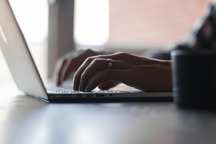 Hands typing on laptop keyboard