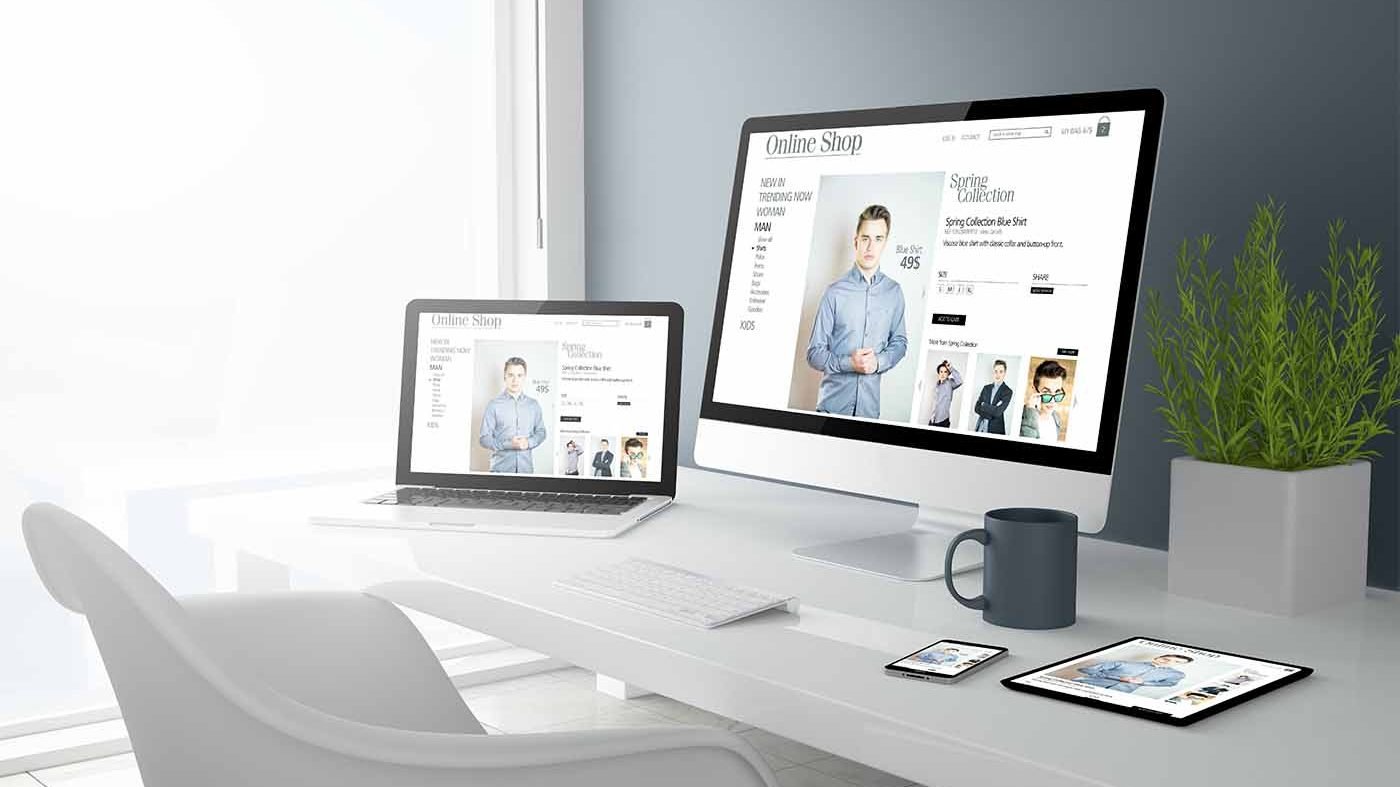 laptop, desktop, tablet and phone showing the same website over a table