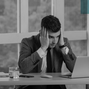 a man looking at his laptop with his hands on his head