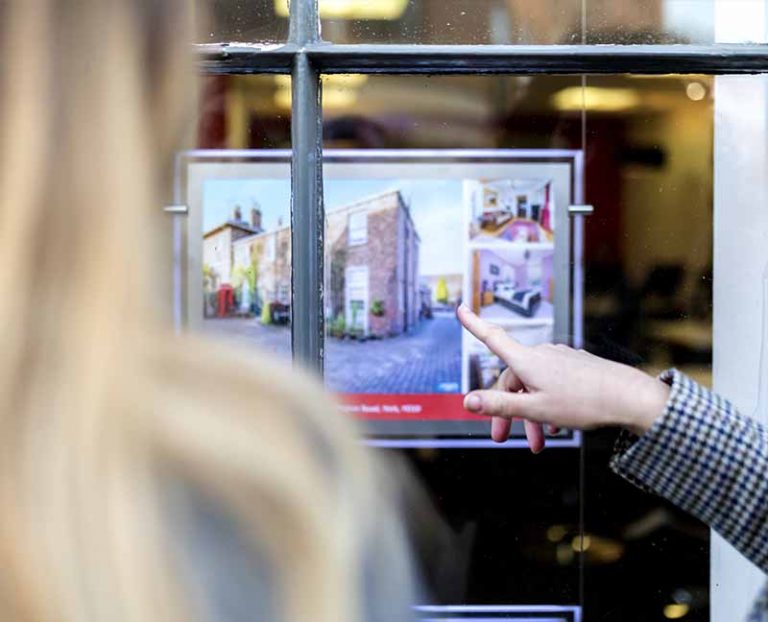 People looking at a house through an estate agency window